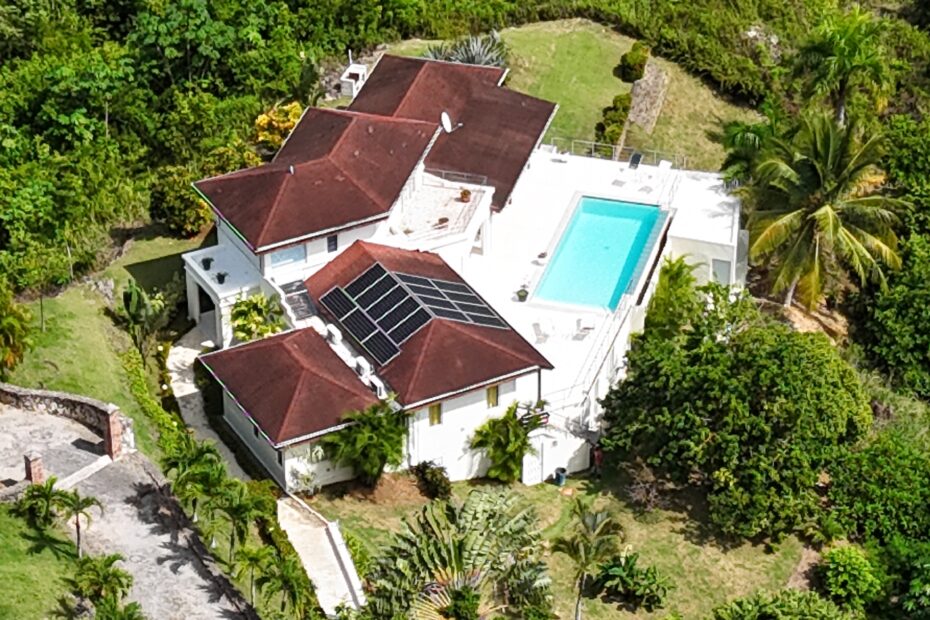Aerial view of a villa and swimming pool surrounded by tropical greenery